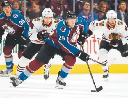  ?? David Zalubowski, Associated Press ?? Avalanche center Nathan MacKinnon advances the puck against the Blackhawks’ Patrick Kane, left, and Nick Schmaltz during the first period of Friday night’s game at the Pepsi Center.