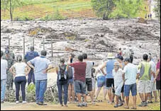  ?? REUTERS ?? Residents look at a road blocked after the dam caved in.