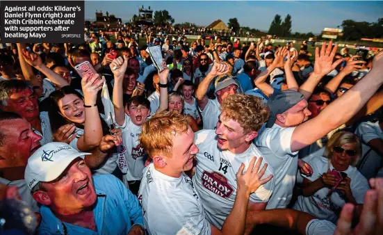  ?? SPORTSFILE ?? Against all odds: Kildare’s Daniel Flynn (right) and Keith Cribbin celebrate with supporters after beating Mayo