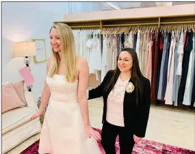  ?? (AP/Gilded Social) ?? Tanya Rutner Hartman, owner of Gilded Social, a bridal shop in Columbus, Ohio, helps a customer try on a gown earlier this month.