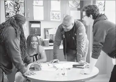  ?? ERIN HOOLEY/CHICAGO TRIBUNE ?? Former Bears player Mickey Pruitt and Walter Payton High School junior Jake Herman, right, help 17-year-old patient Diamond Johnson and her mother, Delilah Alexander, fill out a fantasy football roster at Lurie Children’s Hospital in Chicago.