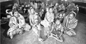  ??  ?? Evacuated villagers look on at a shelter near Berhampura during Cyclone Titli, near Berhampura in eastern Odisha state.