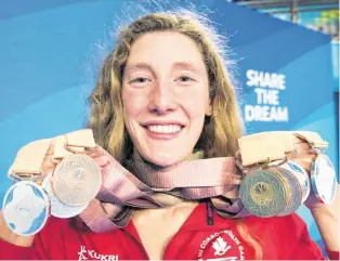  ?? CP PHOTO ?? Taylor Ruck holds up her eight swimming medals at the Commonweal­th Games.