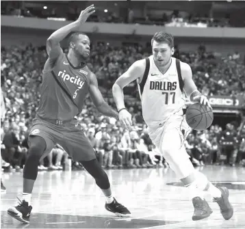  ?? Tony Gutierrez/Associated Press ?? ■ Portland Trail Blazers’ Rodney Hood (5) defends as Dallas Mavericks forward Luka Doncic (77) drives to the basket for a shot in the first half of an NBA game Sunday in Dallas.