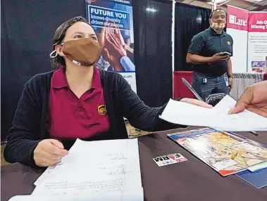  ?? ROGELIO V. SOLIS/ASSOCIATED PRESS ?? A United Parcel Service human resources intern hands a job applicant an informatio­n sheet as the human resources specialist for the company, Mareno Moore, monitors the interactio­n during a job fair Tuesday in Tupelo, Miss. The U.S. Labor Department says 4.3 million people left their jobs in August, the highest on record for a single month.