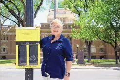  ?? JUNI OGLE/ROSWELL DAILY RECORD ?? Kathy Lay, volunteer and outreach coordinato­r for the city of Roswell, shows one of the “ballot bins” for litter in downtown Roswell. The bins are part of a humorous campaign aimed at reducing cigarette waste in the city by asking people to “vote” on everything from UFOs to New Mexico’s ubiquitous red versus green chile question.