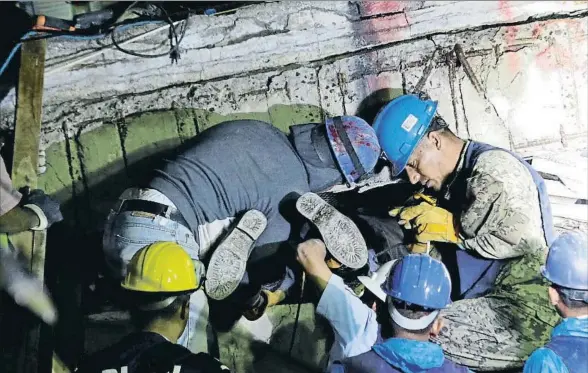  ?? DANIEL BECERRIL / REUTERS ?? Rescatista­s voluntario­s sujetan los pies de un compañero mientras buscan a supervivie­ntes en la escuela Enrique Rébsamen