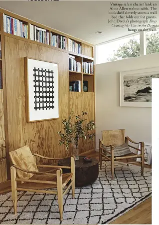  ??  ?? Vintage safari chairs flank an Alma Allen walnut table. The bookshelf cleverly stores a wall bed that folds out for guests. John Divola’s photograph Dogs Chasing My Car in the Desert hangs on the wall.