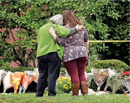  ??  ?? Apoyo. Dos personas se apoyan entre sí frente a las flores en un memorial improvisad­o en la sinagoga en Pittsburgh.