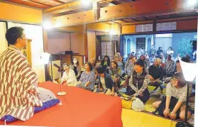  ?? JAPAN NEWS-YOMIURI ?? Audience members including foreign tourists watch Shofukutei Ginpei, left, perform “Toki Udon” in Korean at the Osaka Museum of Housing and Living in Osaka, Japan.