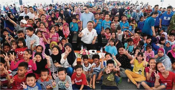  ??  ?? One for the camera: Norashikin, Rahman (centre, in white) and Yakub posing with the children after handing out school bags and stationery sets at the launch of the SL1M open day.