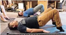  ??  ?? Electricia­n Mariah Densow holds a bridge during Blue Collar Yoga, a class catered to manual laborers at The Modern Prairie Craftsman woodworkin­g shop in Norman.