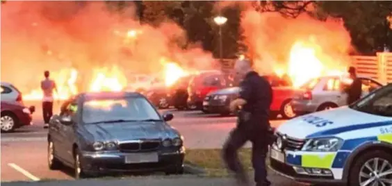 ??  ?? Inferno : Police arrive at one of the scenes of cars burning in Gothenburg, while other officers were pelted with rocks by youths