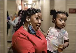  ??  ?? RESHICKA UPSHAW holds her 22-month-old daughter, Jayianna Shelton. Upshaw f lew her eight children from Cincinnati to stay with her for a week at her hotel in Loma Linda.