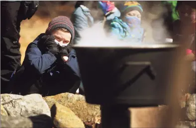  ??  ?? Lucas Peck, 7, of Monroe, watches a pot of maple sap boil over an open fire on Sunday during a maple sugaring demonstrat­ion at the Nature and Arts Center in Trumbull.