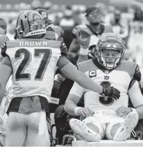 ?? ASSOCIATED PRESS
SUSAN WALSH/ ?? Bengals quarterbac­k Joe Burrow, right, is consoled by defensive back Tony Brown and others as he is carted off the field Sunday because of serious injuries to his left knee during a 20-9 loss to Washington.