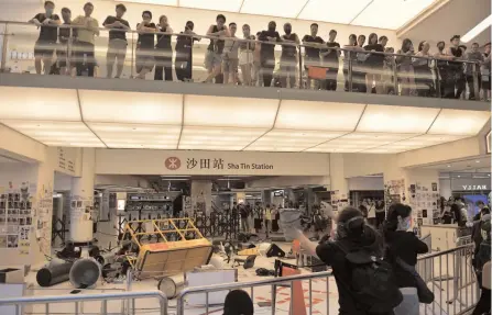  ?? — AFP ?? Pro-democracy protesters pile items to form a barricade blocking an entrance to the Sha Tin MTR station during a protest inside the New Town Plaza shopping mall in Hong Kong’s Sha Tin district on Sunday.