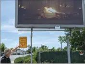  ?? ?? Photograph­er Thomas Broening gestures to one of his billboards in Oroville, which depicts a convertibl­e car on fire.