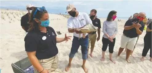  ??  ?? Kate Shaffer, rehabilita­tion manager at the National Aquarium, left, introduces Muenster, a Kemp’s ridley sea turtle,
held by Maryland Lt. Gov. Boyd Rutherford. The turtle was released after being nursed back to health.