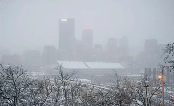  ?? Pam Panchak/Post-Gazette photos ?? Snow squalls obscure the Downtown skyline on Christmas morning.