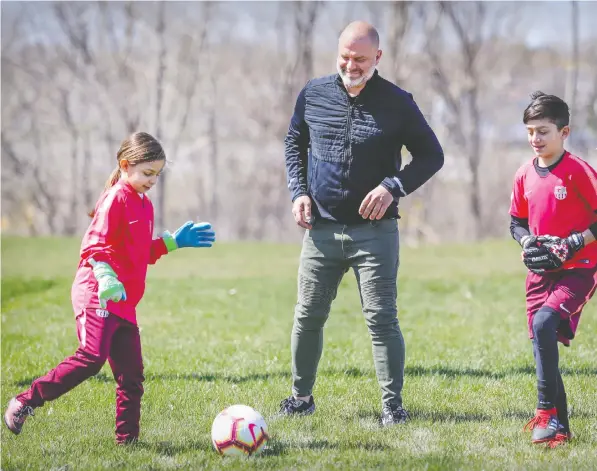  ?? JOHN MAHONEY ?? Mike Smith kicks a ball with children Sofya and James in Laval, Que. Smith is out $2,600 after a soccer academy folded.