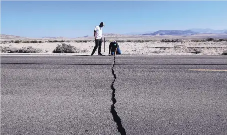  ?? MARCIO JOSE SANCHEZ/ASSOCIATED PRESS ?? Ron Mikulaco, right, and his nephew, Brad Fernandez, examine a crack caused by an earthquake outside of Ridgecrest, California, Saturday.