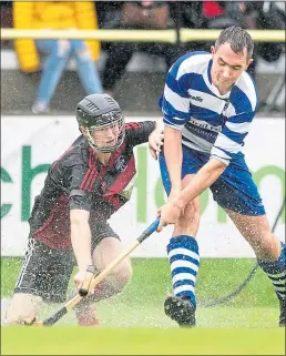  ??  ?? Oban’s Daniel Sloss and Michael Russell of Newtonmore battle each other, and the elements, in the Tulloch Homes Camanachd Cup Final at An Aird, Fort William