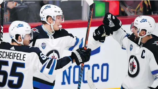  ?? PHOTOS: MARTTI KAINULAINE­N/LEHTIKUVA VIA AP ?? Patrik Laine, centre, celebrates a goal with Mark Scheifele, left, and Blake Wheeler Thursday during a 4-2 Jets win over Florida in Helsinki.