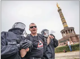  ?? (AP/dpa/Christoph Soeder) ?? A man in front of the Victory Column in Berlin is led away by police officers Sunday during a protest against Germany’s coronaviru­s measures.