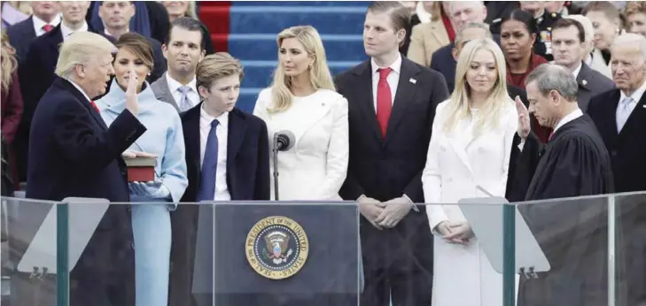  ?? — AP ?? WASHINGTON: Donald Trump is sworn in as the 45th president of the United States by Chief Justice John Roberts as Melania Trump and his family look on during the 58th Presidenti­al Inaugurati­on at the US Capitol in Washington yesterday.