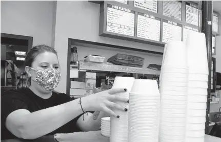  ?? BARBARA HADDOCK TAYLOR/BALTIMORE SUN ?? Rachel Schuman stacks foam containers on the front counter at Captain Dan’s Crab House in Eldersburg on Thursday.