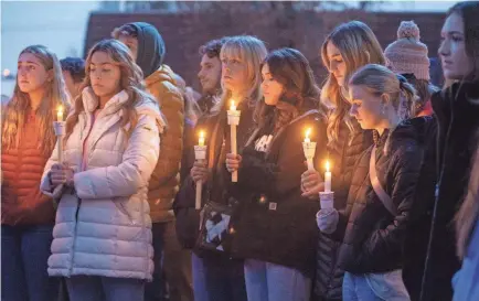  ?? SARAH A. MILLER/AP ?? Boise State University students, along with people who knew the four University of Idaho students who were found killed in Moscow, Idaho, pay their respects at a vigil held in front of a statue on the Boise State campus.