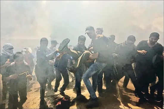  ?? MAHMUD HAMS / AFP ?? Un grupo de palestinos trasladan a un herido durante los enfrentami­entos con el ejército israelí cerca de la frontera entre Gaza e Israel