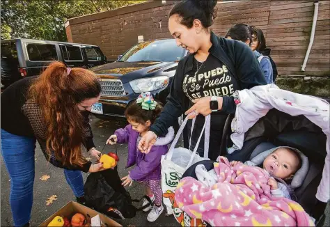  ?? Melanie Stengel / C-Hit.org ?? Laura Garcia passes out food, drinks and flowers to women in the parking lot of a laundromat on Ely Avenue in Norwalk. At right is Yaritea Garcia and her daughters, Emily, 4, and Sophia, 4 months.