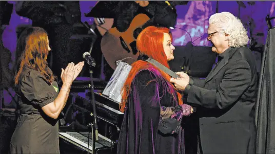  ?? Wade Payne The Associated Press ?? Ricky Skaggs presents Wynonna Judd with her medallion Sunday during the Medallion Ceremony at the Country Music Hall of Fame as sister Ashley Judd, left, looks on in Nashville, Tenn. Their mother, Naomi Judd, died unexpected­ly Saturday.