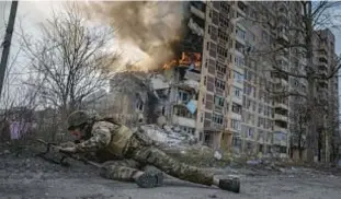  ?? AP ?? A Ukrainian police officer takes cover in front of a burning building in Avdiivka, Ukraine, last year. The second year of Ukraine’s fight against Russia’s invasion brought no respite for Ukrainian soldiers or civilians.