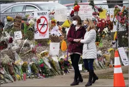  ?? DAVID ZALUBOWSKI — THE ASSOCIATED PRESS ?? Mourners on Thursday walk along the temporary fence put up around the parking lot of a King Soopers grocery store where a mass shooting took place earlier in the week in Boulder, Colo.
