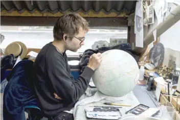  ?? — AFP ?? An artist applies paintwork to a globe at the Bellerby and Co Globemaker­s’ workshop and headquarte­rs in Stoke Newington in north London.