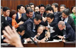  ?? AP/Kyodo News/YOSHITAKA SUGAWARA ?? Members of Japan’s opposition parties try to prevent Shinichi Yokoyama, chairman of the legislatur­e’s Judicial Affairs Committee, from moving to hold a vote on the foreign-labor bill Saturday in Tokyo.