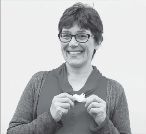  ?? CAROLE MORRIS-UNDERHILL ?? Kate Sircom, the chair of the Hantsport Refugee Sponsorshi­p Committee, shows off a white dove necklace that the group is selling as part of a fundraiser. Each piece has been made and donated by School Street Studio Glass.