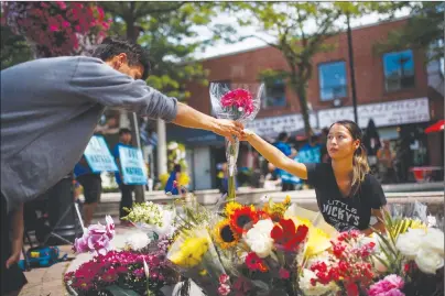  ?? CP PHOTO ?? Kaya Malcolmson, right, and Jowa Malcolmson organize flowers Monday at a memorial site rememberin­g the victims of a shooting on Sunday evening on Danforth Avenue in Toronto.