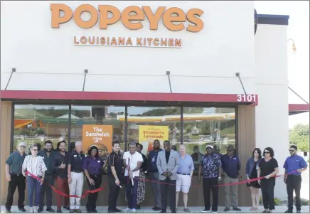  ?? Brodie Johnson • Times-Herald ?? The Forrest City Chamber of Commerce held a ribbon cutting ceremony this week for the new Popeyes location on Highway 1, North of I-40. Business owner Mohammed Qassas holds the big scissors as the ribbon is cut with a smaller pair held by his son Layth Qassas. The father and son duo were joined by members of the staff and community during the event.