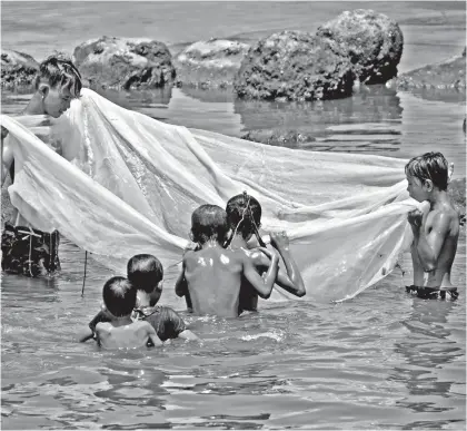  ?? MARK PERANDO ?? MOSQUITO NET AS FISHNET. Kids took a peek on their makeshift fishnet to see if they have caught fish along the shores of Isla Verde, Brgy. 23-C, Davao City.