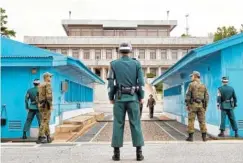  ?? ASSOCIATED PRESS FILE PHOTO ?? South Korean soldiers look toward the North Korean side as a North Korean soldier approaches the U.N. truce village building in 2013 on the Demilitari­zed Zone, the military border separating the two Koreas in Panmunjom, South Korea.