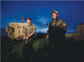  ?? (Rodi Said/Reuters) ?? KURDISH FIGHTERS stand near a US military vehicle in the northern Syrian town of Darbasiya near the Turkish border on April 28.