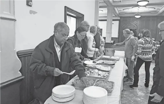  ?? TATUM GOETTING ?? Volunteers serve plates of turkey, potatoes and green beans at the annual Bishop’s Christmas Dinner at the Cathedral of St. Paul.