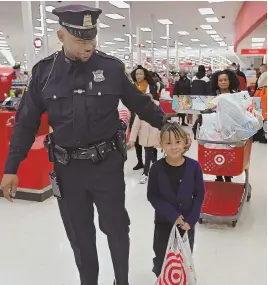  ??  ?? ANYTHING SHE WANTED: Boston police Officer Larry Welch, above, walks with Eliana, 6, and her mother, Sophia Simeon, and their toy haul during the annual ‘Shop with a Cop — Heroes and Helpers’ event at Target in Boston yesterday. Amya, 13, shops with...