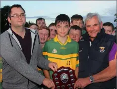  ??  ?? Cathal Roche receives the shield from Dean Goodison (People Newspapers) and Bobby Goff (Coiste na nOg Chairman).