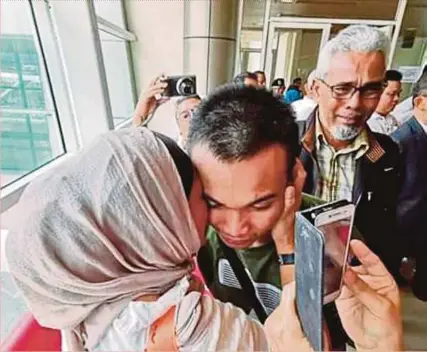  ?? PIC COURTESY OF ABDUL KARIM ABDUL RAHMAN ?? Abdul Mustaqqim Abdul Karim hugging his mother as his father, Abdul Karim Abdul Rahman (right), looks on at the Kuching Internatio­nal Airport yesterday.