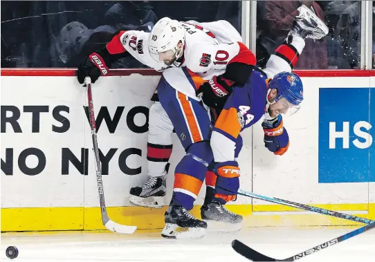  ?? ADAM HUNGER/THE ASSOCIATED PRESS ?? The Senators’ Tom Pyatt is sent airborne into the boards by Islanders defenceman Calvin de Haan on Sunday in Brooklyn. New York won 4-2.